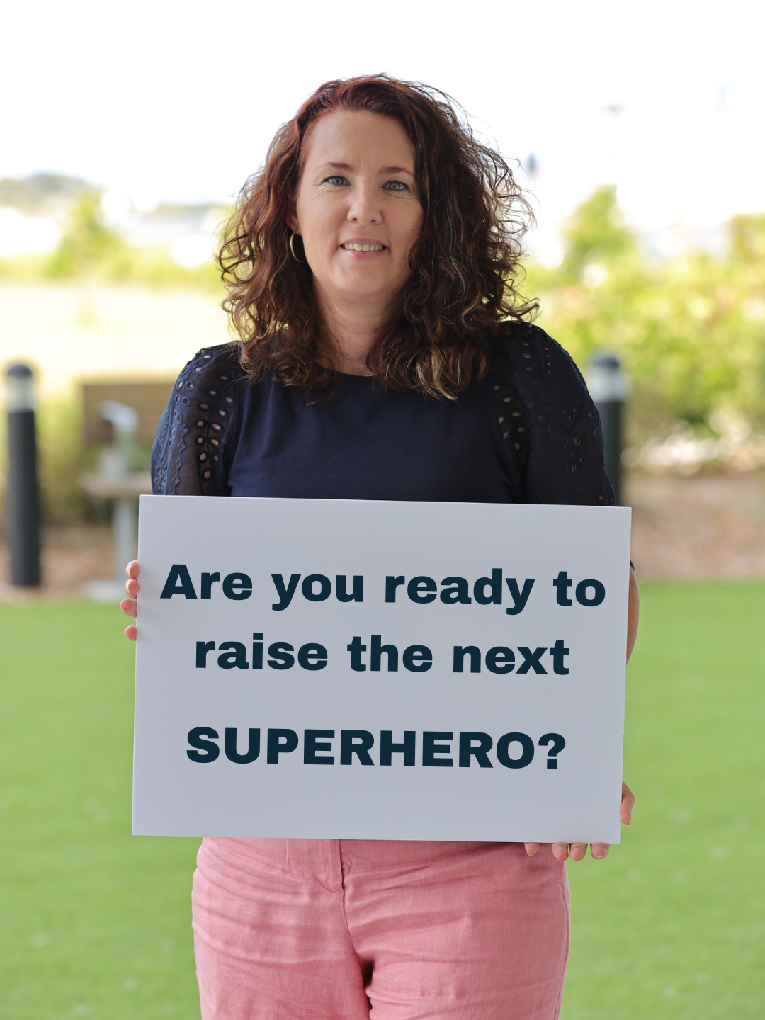 Simone Robinson holding a sign that reads: Are you ready to raise the next superhero?